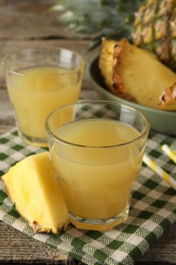 Bardakta nefis ananas suyu ve ahşap masada taze meyve dilimi, yakın plan.