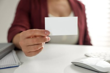 Ofisteki masada boş bir kartvizit tutan kadın, yakın plan. Tasarım için model