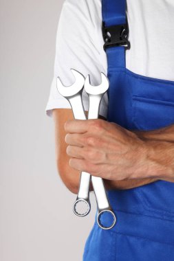 Açık gri arkaplanda anahtarı olan oto tamircisi, yakın plan
