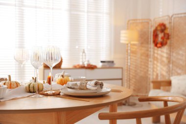 Yemek odasında güzel bulaşık takımları ve sonbahar dekoru olan şık bir masa.