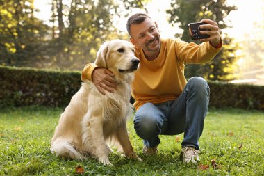 Tatlı Golden Retriever köpeğiyle gülümseyen adam bahar günü selfie çekiyor.