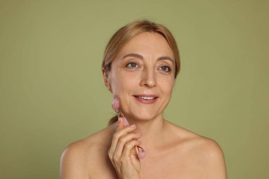 Gülümseyen kadın yeşil arka planda kendi kendine masaj yapıyor.
