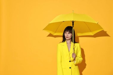 Woman with open umbrella on yellow background, space for text clipart