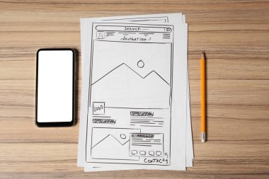 Web sitesi geliştirme. Kablolar, kalem ve akıllı telefon çizimleri ahşap masada, düz yerde.
