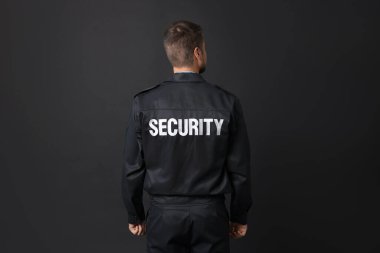 Siyah arka planda üniformalı güvenlik görevlisi.