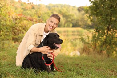 Sonbahar günü sevimli köpeğiyle dışarıda gülümseyen adam. Metin için boşluk