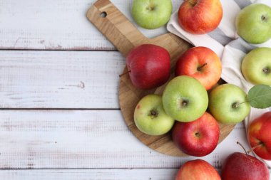 Beyaz ahşap masa üzerinde farklı olgun elmalar, düz uzanmış. Metin için boşluk