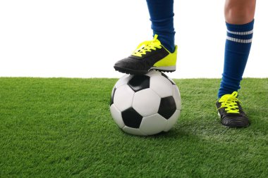 Beyazların arka planına karşı suni çimlerde futbol topu taşıyan futbolcu, yakın plan