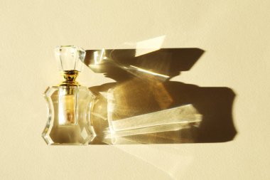 One perfume bottle casting beautiful shadow on beige background, top view clipart