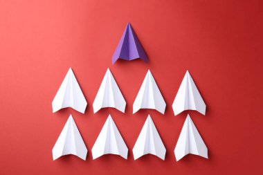 Paper planes on red background, top view