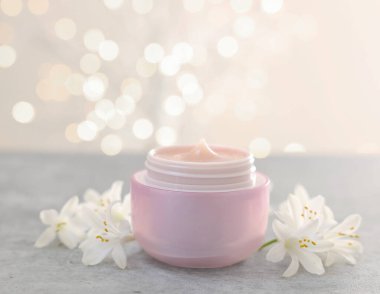 Kavanozda krema ve gri masada güzel yasemin çiçekleri, arka planda bulanık ışıklarla, yakın plan. Metin için boşluk