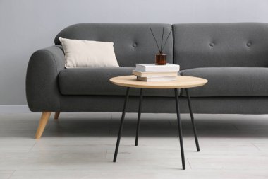 Rahat bir kanepe ve gri duvarın yanındaki masa.