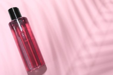 Pembe arka planda şampuan şişesi, üst manzara. Metin için boşluk