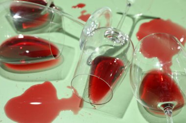 Açık yeşil arka planda kırmızı şarap dökülmüş bardaklar, yakın plan.