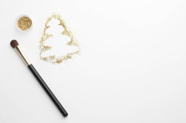 Beyaz arka planda parıltı ve makyaj fırçasından yapılmış Noel ağacı, düz. Metin için boşluk