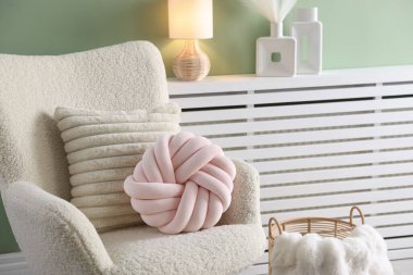 Oturma odasındaki hafif koltukta dekoratif yastıklar.