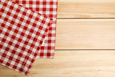 Hafif ahşap masa üzerinde kareli desenli katlanmış masa örtüsü, üst manzara. Metin için boşluk