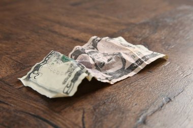 Tahta masanın üzerine buruşmuş bir dolar banknot, yakın plan.