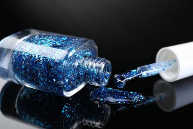 Şişedeki tırnak cilasını aç ve siyah ayna yüzeyinde fırçala, yakın plan.