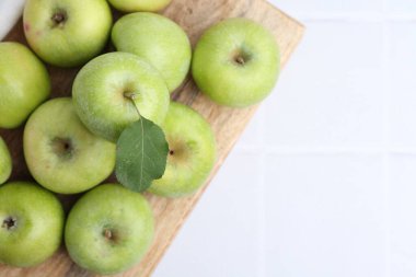 Beyaz fayanslı masa üzerinde taze yeşil elmalar, üst manzara. Metin için boşluk