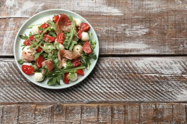 Lezzetli salata roka, mozzarella peyniri, domates ve ahşap masa, üst manzara. Metin için boşluk