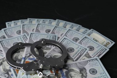 Yozlaşma. Kelepçe ve dolar banknotları siyah masaya, yakın plan.