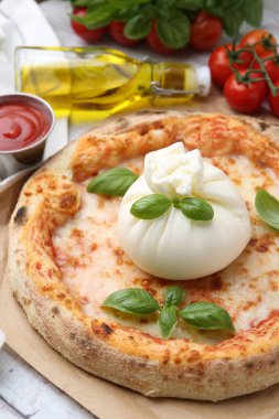 Masada servis edilen burrata peynirli lezzetli pizza, yakın plan.