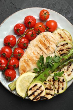 Lezzetli ızgara sebzeler ve siyah desenli masada tavuk göğsü.