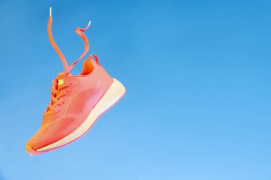 Açık mavi arkaplana karşı havada şık bir spor ayakkabı, metin için boşluk