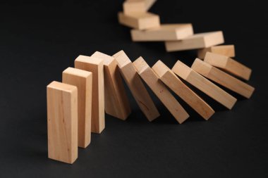 Domino etkisi. Tahta bloklar siyah arkaplana düşüyor