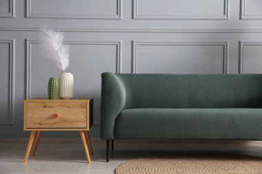 Rahat bir kanepe ve gri duvarın yanındaki yan masa.