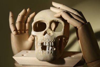 Human skeleton made of skull, wooden blocks and mannequin hands on beige background, closeup clipart