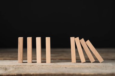 Domino etkisi. Tahta bloklar siyah arkaplana karşı masaya düşüyor