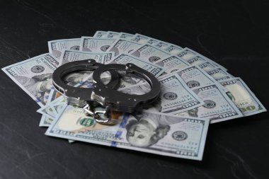 Yozlaşma. Kelepçe ve dolar banknotları siyah masaya.