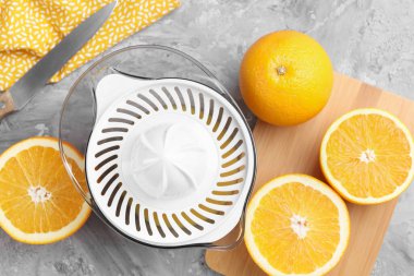 Plastik sıkacağı, portakallar ve bıçak gri masada, üst manzara