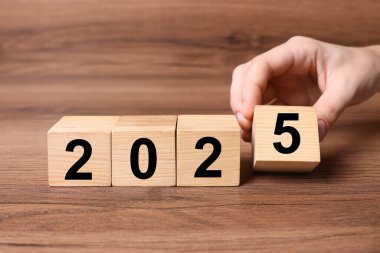 2025 Yeni Yıl. Masaya 5 numaralı tahta küpü koyan kadın, yakın plan.