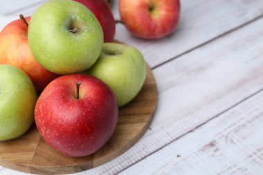 Beyaz ahşap masada farklı olgun elmalar, yakın plan. Metin için boşluk