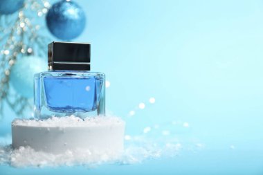 Parfüm şişesi ve açık mavi arka planda kar olan Noel kompozisyonu, yakın plan. Metin için boşluk