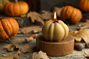 Sonbahar atmosferi. Yanan balkabağı şekilli mum ve kuru yapraklar ahşap masada, yakın plan.