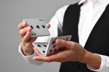 Gri arka planda profesyonel krupiye karıştırma kartları, yakın plan