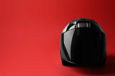 Kırmızı arka planda güneşliği olan modern motosiklet kaskı, metin için boşluk