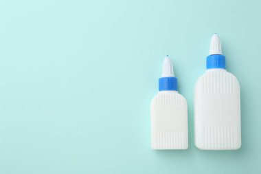 Turkuaz arka planda bir şişe yapıştırıcı. Metin için boşluk