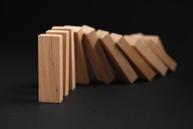 Domino etkisi. Tahta bloklar siyah arkaplana düşüyor