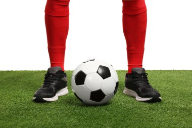 Beyazların arka planına karşı suni çimlerde futbol topu taşıyan futbolcu, yakın plan
