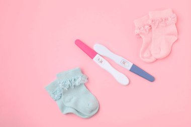 Hamilelik testleri ve pembe arka planda çoraplar, üst görünüm