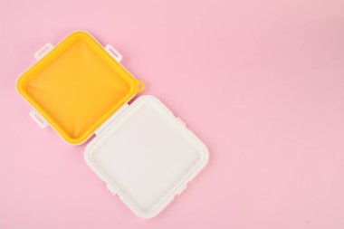 Açık pembe arka planda, üst manzaralı plastik sandviç kutusu. Metin için boşluk