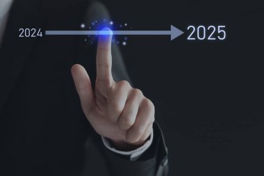 Yeni yıl hedefleri. İşadamı 2024 'ten 2025' e kadar kara arkaplana karşı sanal ekranda oklara dokunuyor.