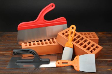 Kırmızı tuğlalar ve tahta bıçaklar. Yapı malzemeleri ve inşaat araçları