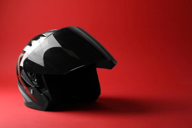 Kırmızı arka planda güneşliği olan modern motosiklet kaskı, metin için boşluk