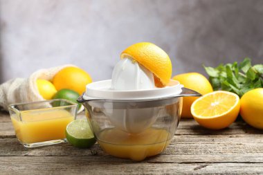 Plastik sıkacağı ve taze portakallar ahşap masada, yakın plan.